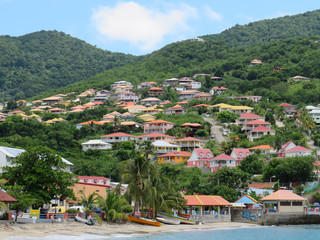 Panoramic view of the small coastal town of Anses d'arlet. Colored houses on hill with abundant...