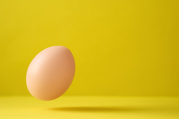 Chicken Egg Falling On Ground Against Yellow Background