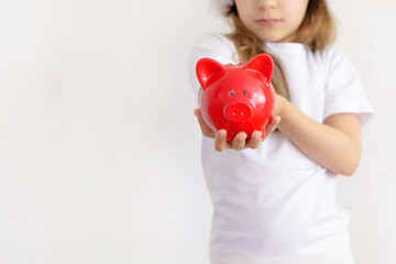 Fototapeta na wymiar Young child girl in a Santa hat keeps a piggy Bank isolated.
