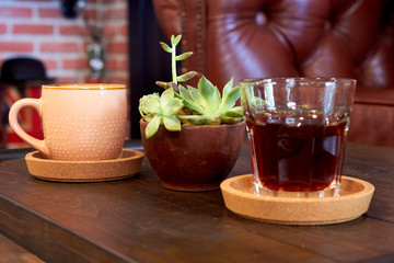 Glass with coffee, cup with water and a flower pot on the table
