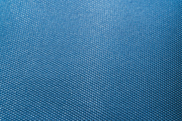 Fototapeta na wymiar Close-up of abstract flat blue high detail textured clothing fabric pattern background in partial focus and realistic light reflections