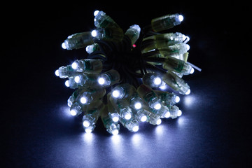 Glowing cold white led pixels christmas holiday lights on black background.