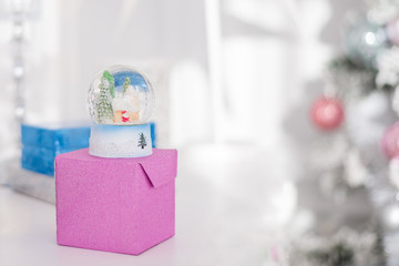 surprise, gift, snow ball, gift box Christmas background in bright colors. Christmas decoration, snow dome, globe with table decoration