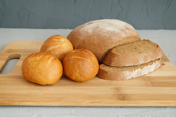 rye bread and scones on wooden Board on grey background