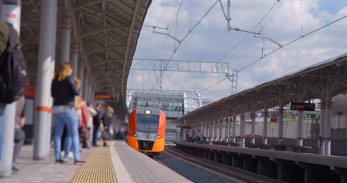 The platform of the ground station of the metro is full of passengers and the train is just arriving