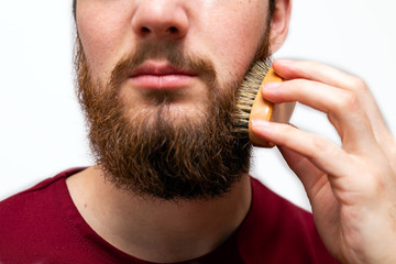 closeup of handsome man brushing his beard on white background isolated