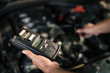 Close-up of car mechanic using diagnostic tool in a auto repair shop.