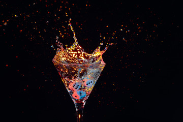 Dice fall in a glass of martini. Colourful cocktail in glass with splash.