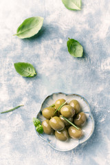 Green olives on bright wooden background. Top view. Close up. Copy space. 