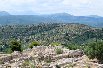 Fototapeta na wymiar Ruins of ancient greek city Mycenae acropolis with hills coverd by olive trees on the background
