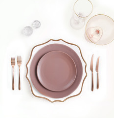 New luxury white and pink ceramic plate, copper cutlery view from above on a isolated background. Top view. Knife and fork for a festive table for a wedding, birthday or party.
