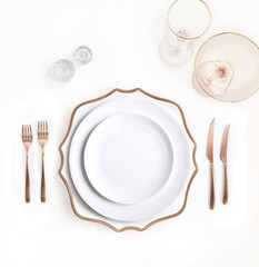 New luxury white ceramic plate, copper cutlery view from above on a isolated background. Top view. Knife and fork for a festive table for a wedding, birthday or party.