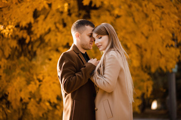 Loving beautiful couple walking in an autumn park in an oak grove. Photoshoot in the autumn forest. Leaf fall, yellow leaves
