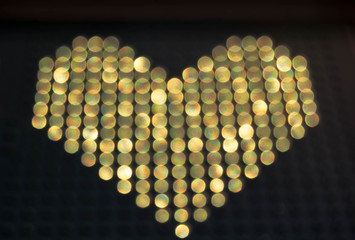  Image of a heart of gold color from blurry luminous circles. A symbol of love in the form of night lights with a blur effect. Festive heart. Valentine's Day.