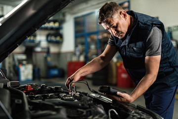 Fototapeta na wymiar Car mechanic analyzing amperage of car battery in a repair shop.