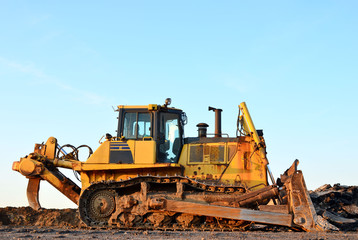 Track-type bulldozer, earth-moving equipment. Land clearing, grading, pool excavation, utility trenching, utility trenching and foundation digging during of large construction jobs.
