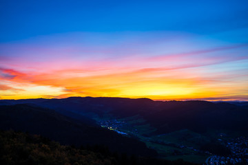 Fototapeta na wymiar Germany, Colorful sunset sky decorating black forest hills and mountains nature landscape surrounding houses of a village, aerial view above