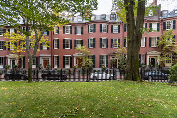 Exterior of traditional American brick Row houses along street with a fenced garden in foreground...