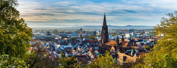 Gordijnen Germany, XXL panorama of city freiburg im breisgau skyline with cathedral muenster in old town in warm sunset light in romantic autumn season, aerial view above cityscape © Simon