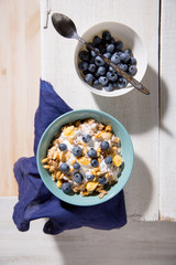 Bowl of granola with yogurt and raspberry on a white wooden background