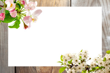 Spring card concept. Natural wooden background, white sheet of paper with spring flowers.