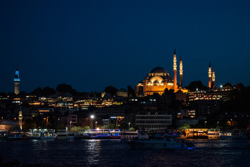 Fototapeta na wymiar Istanbul, Turkey, Middle East: night skyline of the city with view of boats in the Golden Horn and the illuminated Suleymaniye mosque, Ottoman imperial mosque commissioned by Suleiman the Magnificent 