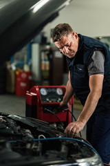 Auto mechanic checking car air conditioning system in a repair shop.