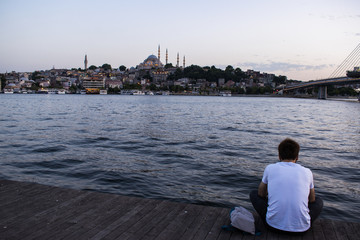 Fototapeta premium Istanbul: people from behind chasing sunset with view of the skyline of the city and the Suleymaniye mosque, Ottoman imperial mosque ordered by Suleiman the Magnificent and designed by Mimar Sinan