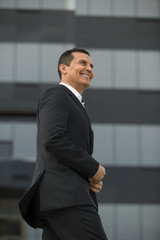 Fototapeta premium Handsome Latino executive man leaving office, talking on the phone and wearing casimir suit