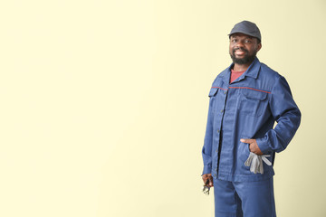 Fototapeta premium African-American car mechanic on color background