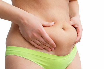 two woman's hand holds a fold of excess fat on the stomach. on white background, side view
