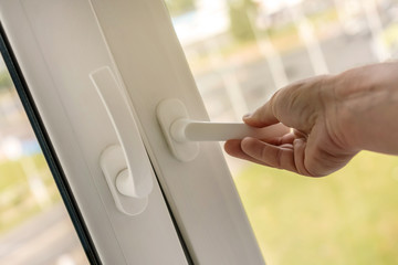 male man hand open plastic frame window holding white handle for airing of room