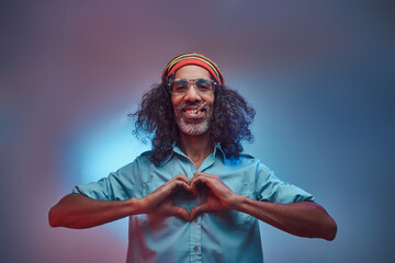 African Rastafarian smokes weed and showing heart symbol and shape with hands. Isolated on a blue...