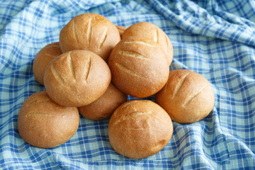 a few small round buns lie on the blue checkered fabric