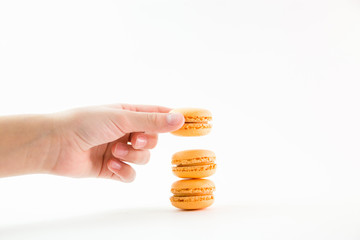 Macaroons on a white background and hand holding one and folding them into a tower, colorful macaroons, selective focus