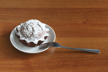 chocolate cake in a saucer on a brown background under the tree