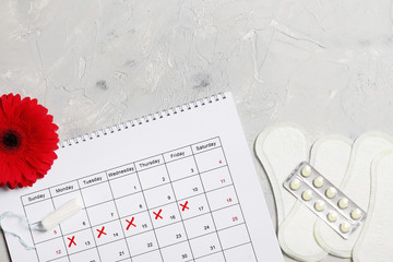 Gerbera, menstrual calendar, pills and tampons on a gray background. Ovulation concept. menstruation concept.