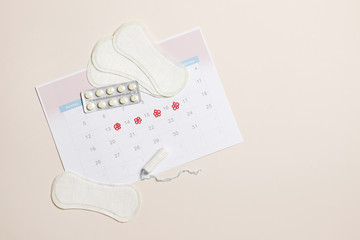 Gerbera, menstrual calendar, pills and tampons on a pink background. Ovulation concept. menstruation concept.