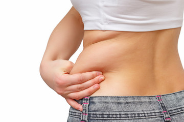 the girl takes extra fat on the sides of her stomach with her hand. isolate on white background