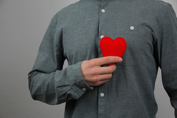 guy holds a red heart model in his hand in his hand, as a symbol of a declaration of love, concept...