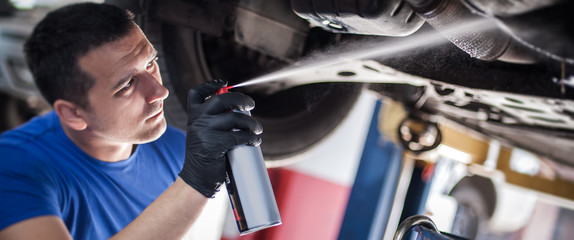 Car master mechanic repairer lubricates screws with machine cleaner spray - obrazy, fototapety, plakaty