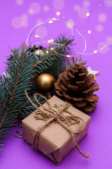Christmas composition of fir branches, gift, Christmas toys, garlands on a purple background. Concept photo Christmas and New Year holiday, gifts.