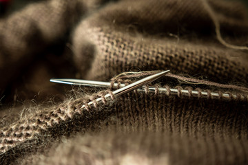 Brown sweater during knitting with yarn on the needles macro photography