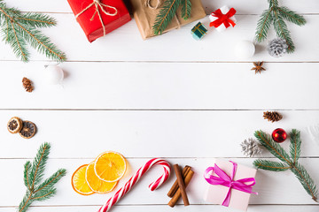 Beautiful Christmas composition on wooden white background with Christmas gift boxes, snowy fir branches, conifer cones, holiday decoration, caramel stick. New Year. Top view, copy space.