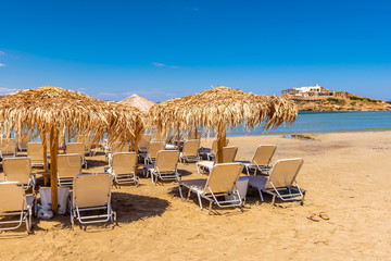Sunbeds with umbrellas on Agios Georgios beach, very popular resort on Naxos island, Greece. - obrazy, fototapety, plakaty