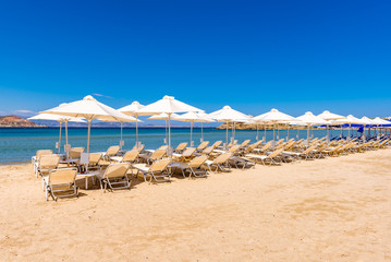 Sunbeds with umbrellas on Agios Georgios beach, very popular resort on Naxos island, Greece.