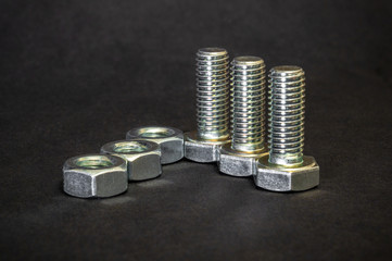 Metal bolts and nuts on black background are used in construction