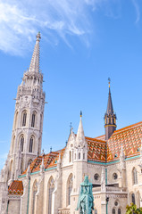 Fototapeta na wymiar Tower of the Matthias Church in Budapest, Hungary on a vertical photo. Roman Catholic church in the Gothic style. Located in front of Fishermans Bastion in Buda Castle District. Tourist attraction