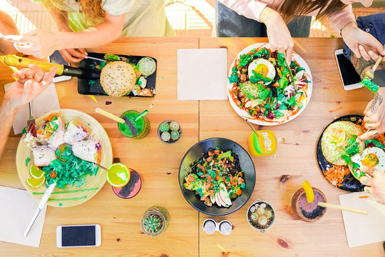 Top view of the vegetarian food, colored smoothie bowl in the bar outdoor. Erasmus students chatting and eating in the vegan and vegetarian restaurant - Food, drink and friendly concept - Focus on the
