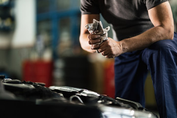 Unrecognizable auto mechanic cleaning his dirty hands in repair shop.